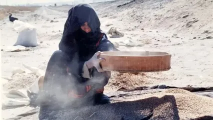 الک کردن خاک توسط زن ساکن بلوچستان، برای پیدا کردن دانه ای گندم!