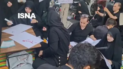 پلاکارد‌ نویسی برای عزاداران به دو زبان فارسی و انگلیسی در خیابان کارگر جنوبی